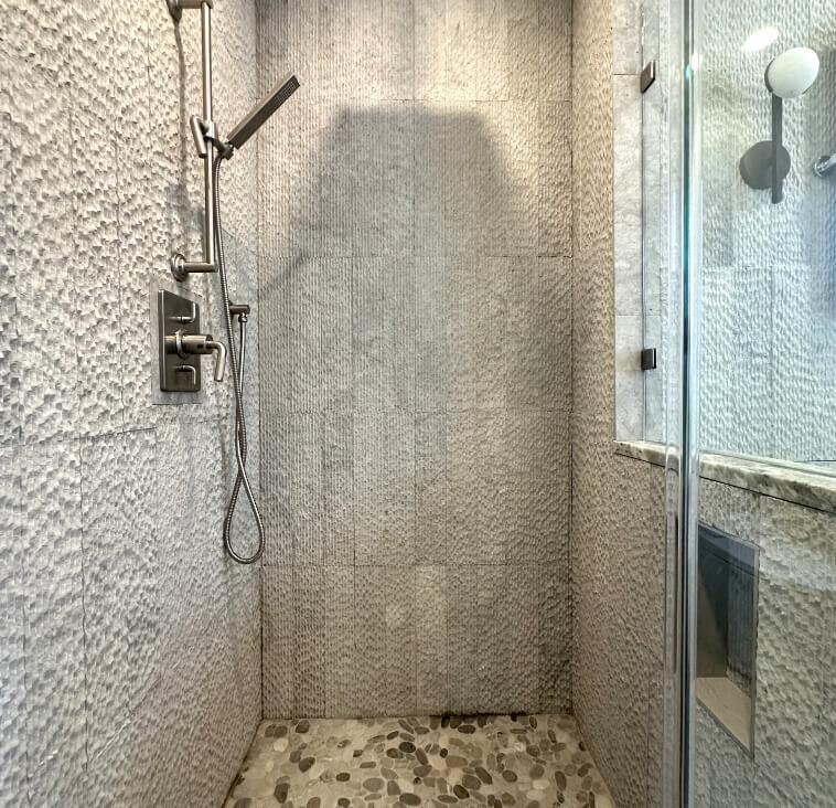 A sleek modern shower with textured walls and a glass enclosure.